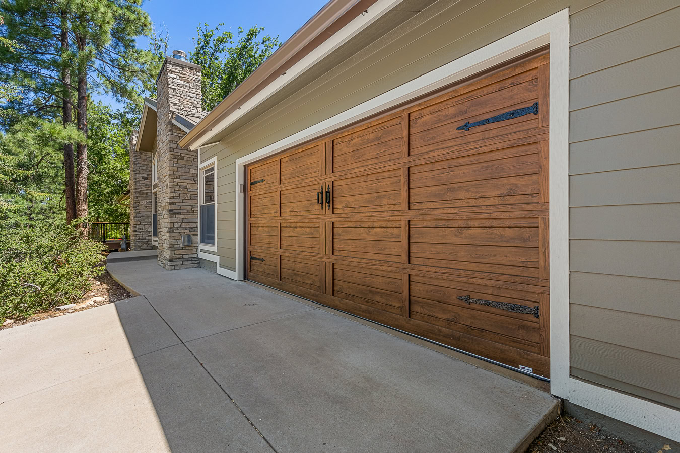 Refinished wooden garage doors on a house with neutral colored siding
