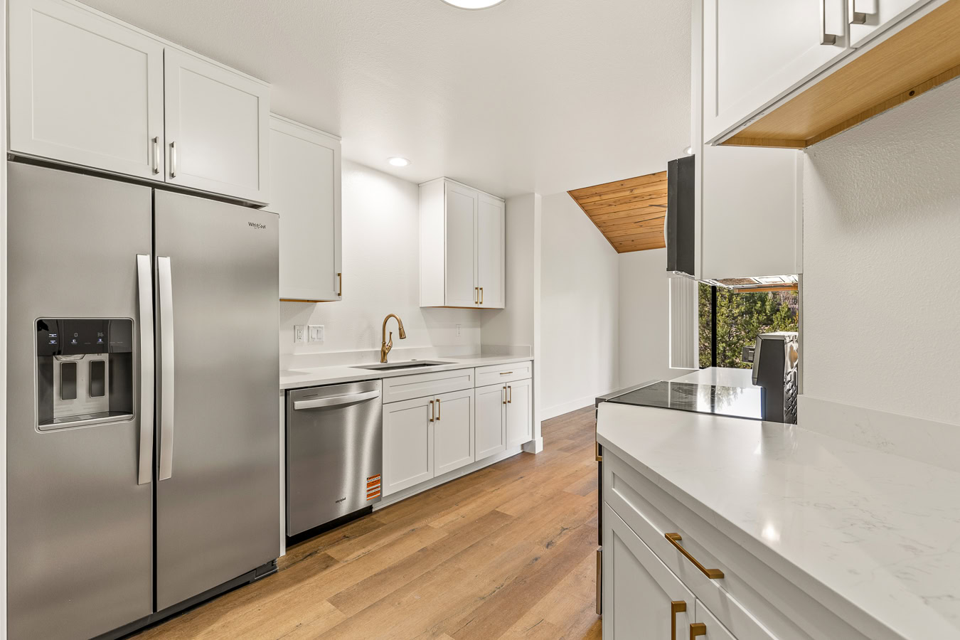 remodeled kitchen with white cabinetry, brass hardware details and a silver refrigerator
