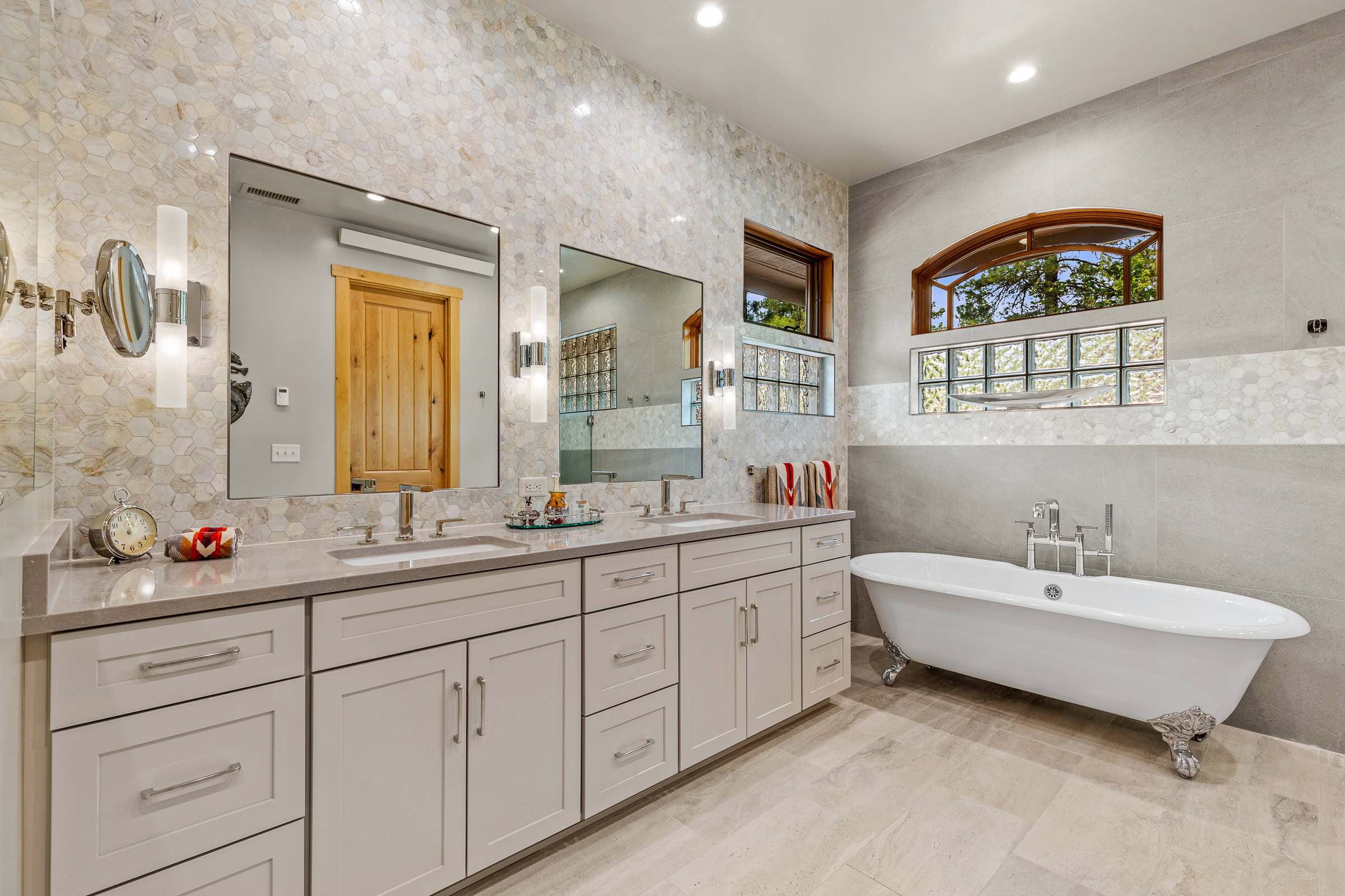 refinished bathroom with clawfoot bathtub, two sinks, two mirrors and plenty of storage
