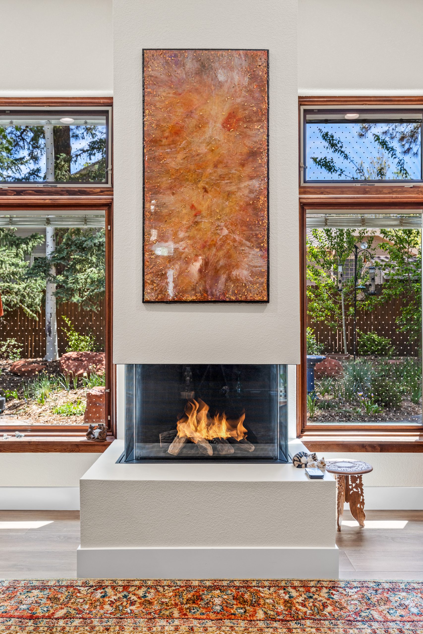beautiful fireplace with a glass enclosure, and copper detailing and art piece