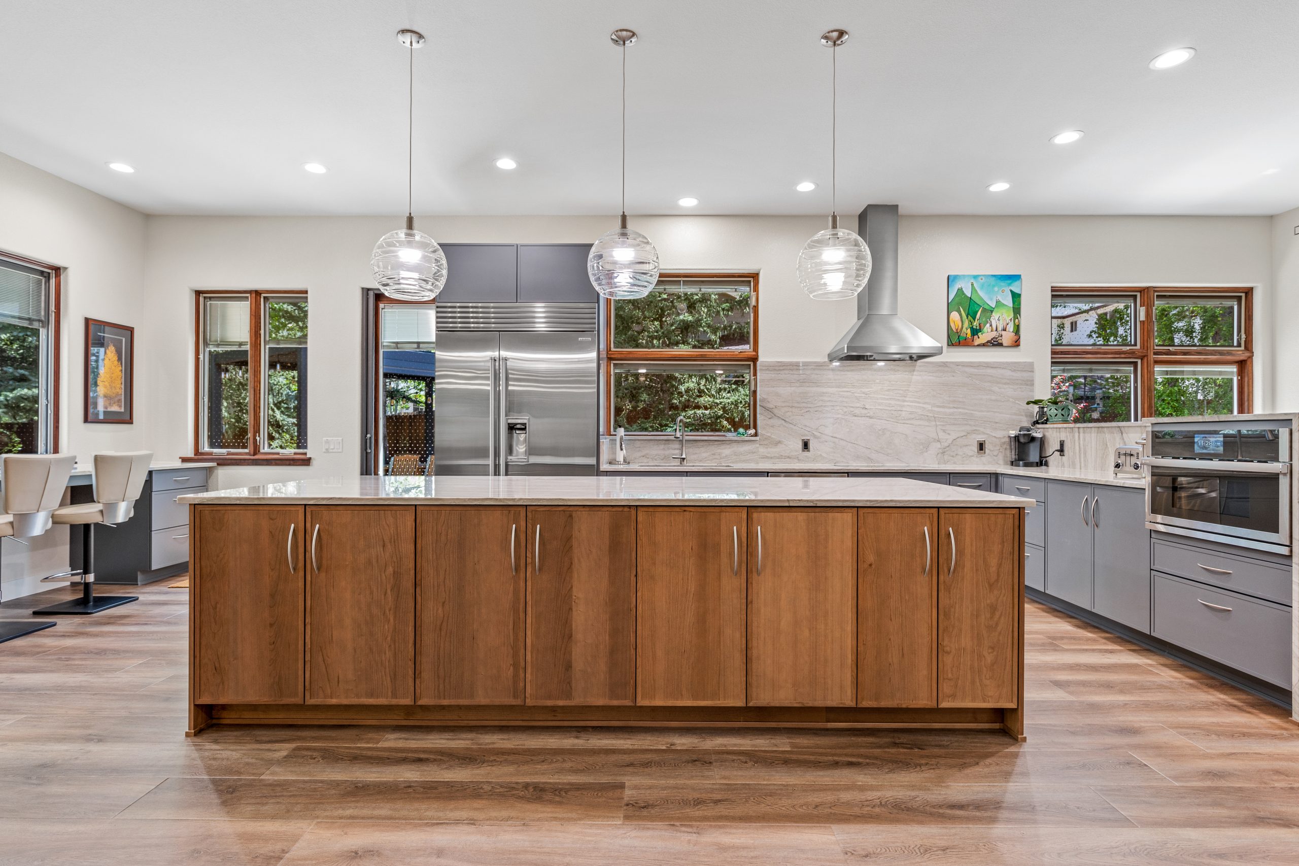 remodeled kitchen with a large island, window bar seating, half wall oven and windows